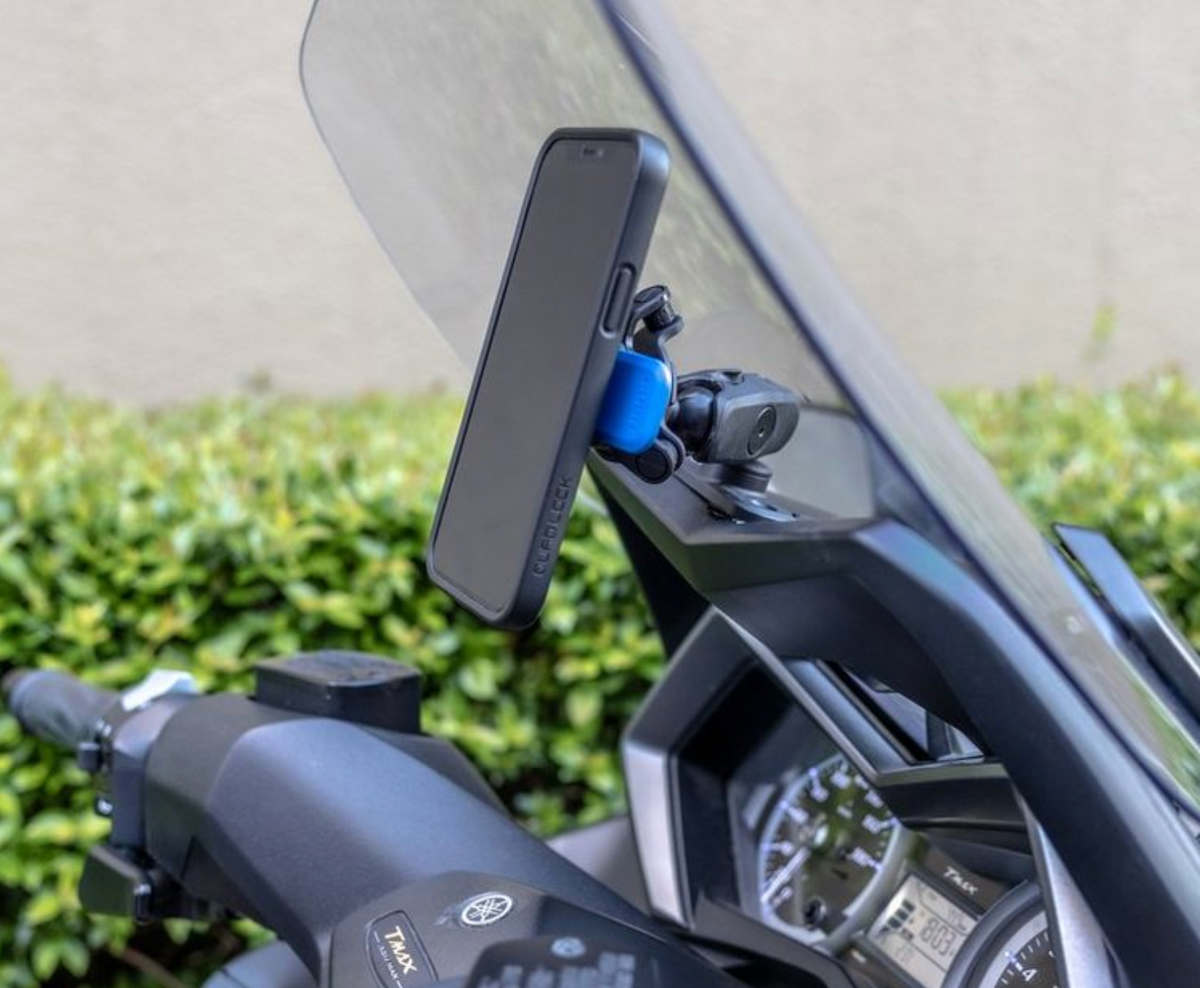 QuadLock 360 Dual Pivot Arm monterad på en motorcykel med en mobiltelefon. Säker och flexibel lösning för navigering och handsfree-användning.