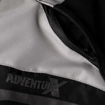 Närbild av RST Textil Mc-Jacka Adventure-X med Adventure-X-logotyp och slitstarkt textilmaterial i grå och svart.